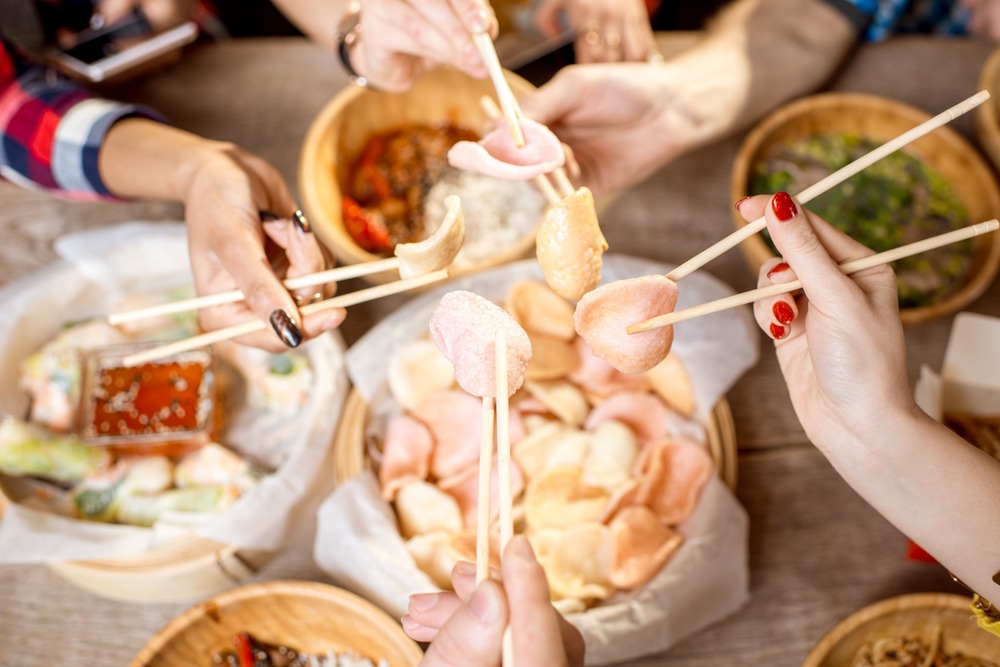 manos con palillos recogen comida china de centro de mesa